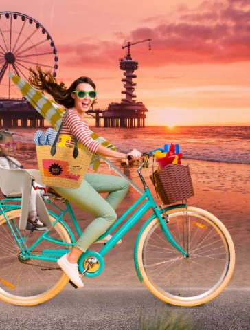 Fictief beeld van een vrouw op een fiets op het strand in Scheveningen en een kindje achterop